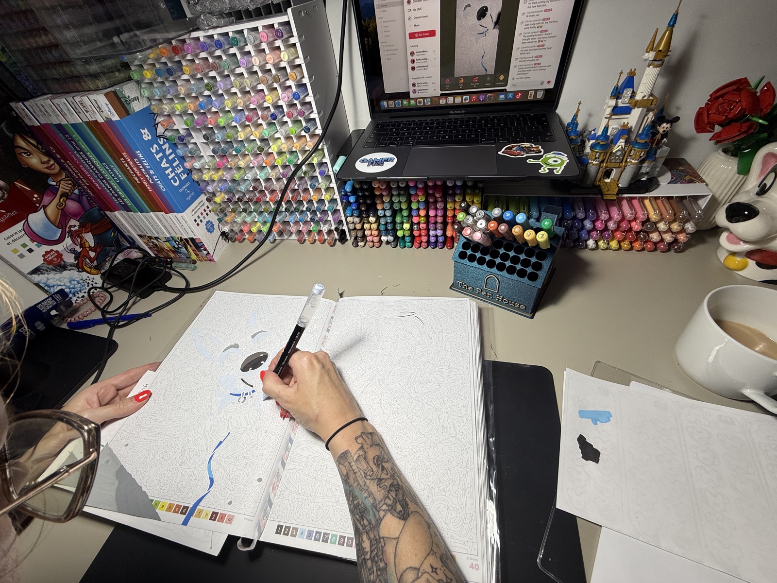 Drawing at a desk with The Pen House full of markers in the background